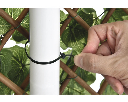 Iemand bevestigt een privacyscherm met een kabelbinder aan een paal.