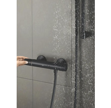 Foto van een thermostatische douchekraan met een hand die de temperatuurregelaar bedient.