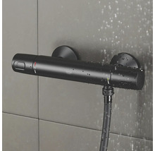 Zwarte Grohe douchethermostaat met doucheslang aan betegelde muur