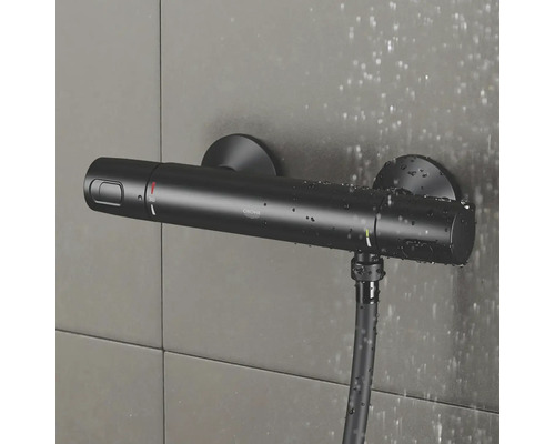 Zwarte Grohe douchethermostaat met doucheslang aan betegelde muur