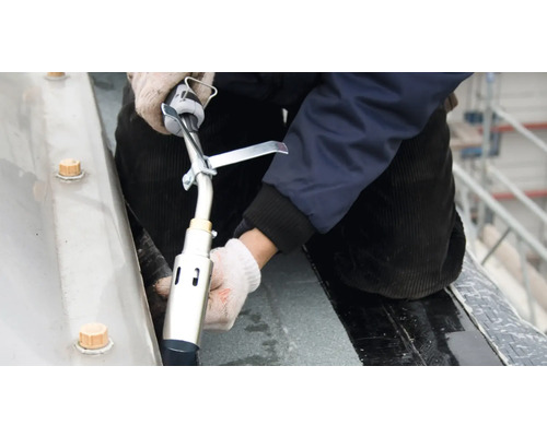 Dakdekker werkt met een brander aan een dakafdichting.