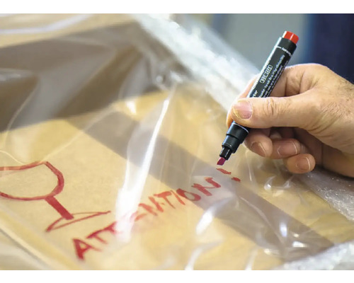 Een hand schrijft met een stift het woord Achtung en een glas symbool op een transparante verpakking.