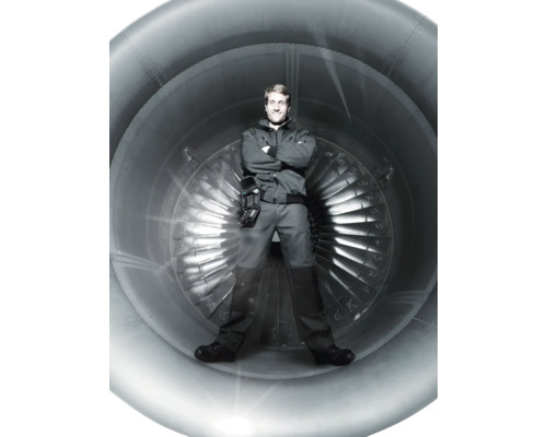 Een man staat voor een vliegtuigmotor.