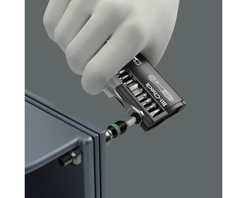 Een hand met handschoen gebruikt een bitcheck gereedschapsset op een schroef.