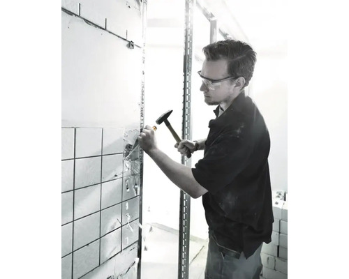 Ambachtsman verwijdert tegels met hamer en beitel.