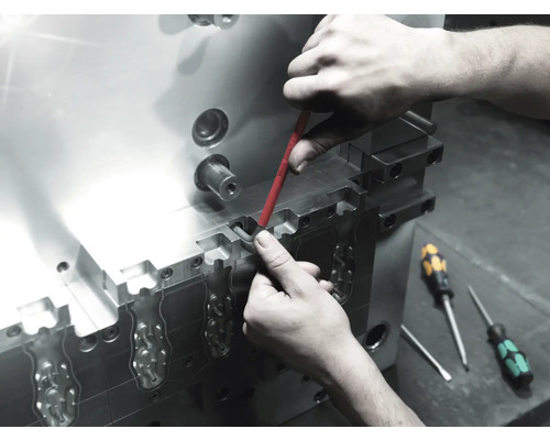 Een werknemer voert met een schroevendraaier onderhoud uit aan een metalen gereedschap.