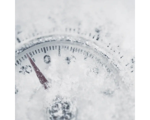 Close-up van een thermometer bedekt met sneeuw, die een temperatuur onder nul aangeeft.