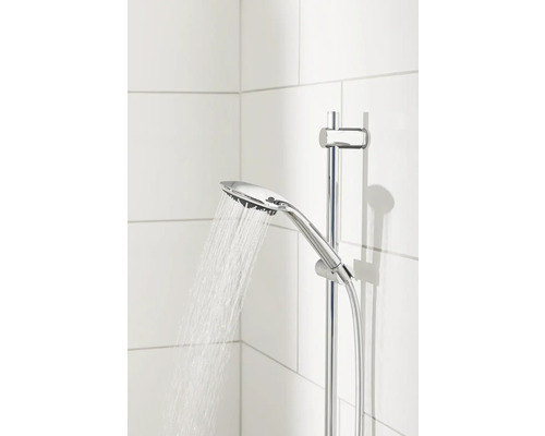 Handdouche met glijstang en stromend water tegen een witte tegelachtergrond.