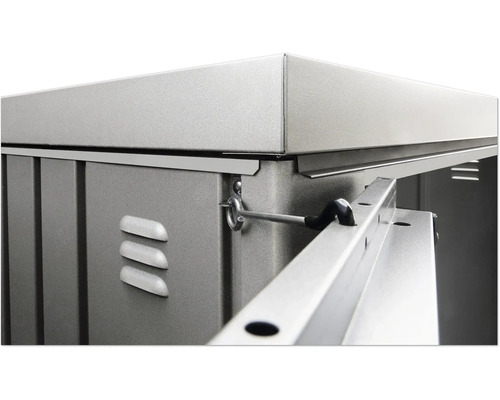 Detailopname van een tuinhuis met metalen elementen, ventilatiesleuven en een vergrendelingsmechanisme.