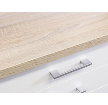 Detailopname van een ladekast met een lichtbruin houten blad en witte lades met zilverkleurige handgrepen.
