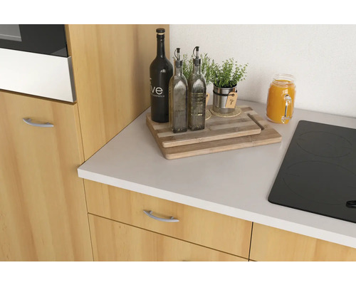 Keukenscène met fornuis, snijplank, olieflessen, kruiden en een inmaakglas op een aanrecht.