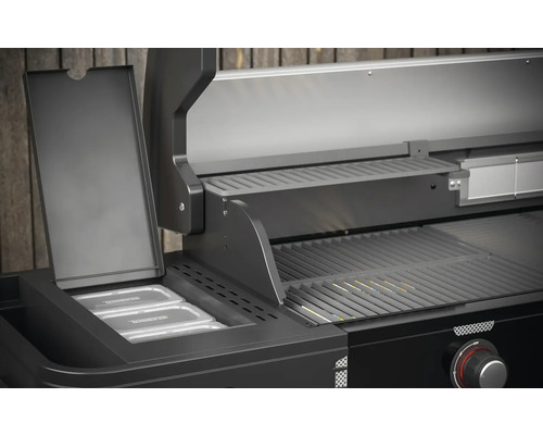 Detail van een zwarte gasbarbecue met warmhoudrooster en containers