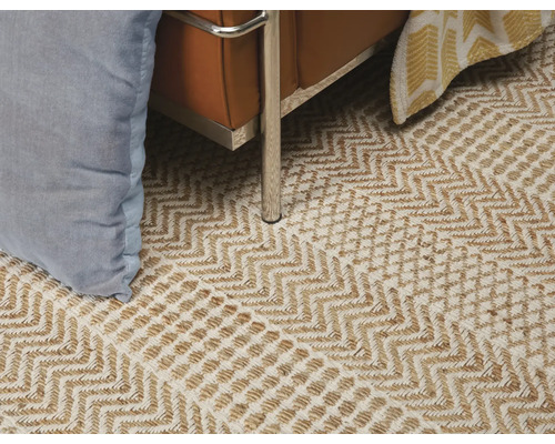 Detail van een vloerkleed met een zigzagpatroon onder een fauteuil