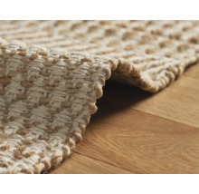 Detail van een gevlochten vloerkleed op een houten vloer