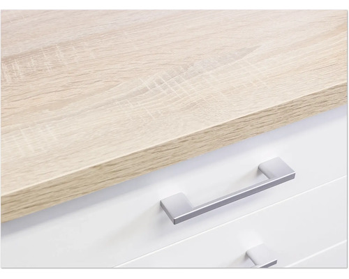 Detailopname van een ladekast met lichtbruin houten blad en zilverkleurige handgrepen