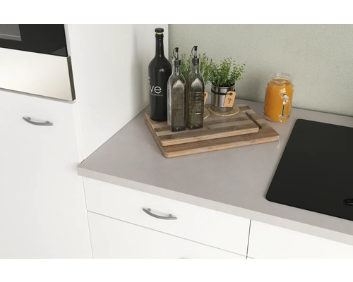 Keukenstilleven met snijplanken, olieflessen, kruiden en een glas sap op een aanrecht.