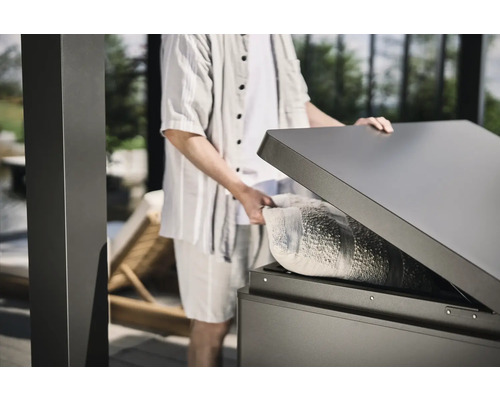 Persoon opent een weerbestendige opbergbox buiten met een kussen erin.