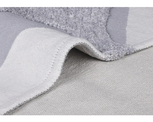 Detailopname van een grijze badmat met pool en geweven achterkant.