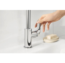 Glanzende wastafelkraan met eenhendelmengkraan en Grohe logo wordt bediend door een hand.
