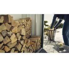 Vrouw vult vuurkorf met hout uit een houtopslag