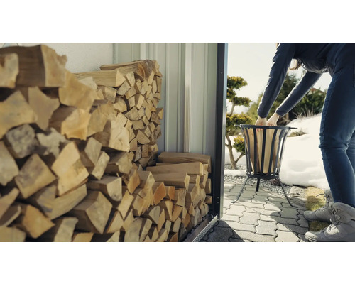 Vrouw vult vuurkorf met hout uit een houtopslag