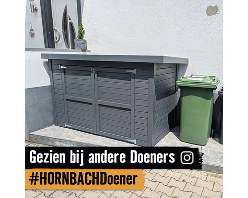 Grijze afvalbakombouw met een groene afvalbak ernaast