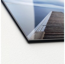 Close-up van een acrylglasplaat met een motief van een houten steiger aan het water.