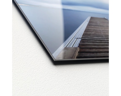 Close-up van een acrylglasplaat met een motief van een houten steiger aan het water.