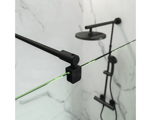 Detailopname van een douchecabine met zwarte beugel en douchekop voor een marmeren wand