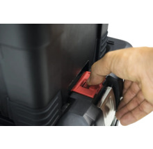 Detailopname van een gereedschapskist met rode sluiting die door een hand wordt bediend.