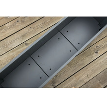 Grijze plantenbak met drainagegaten op houten terras