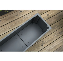 Lege, grijze plantenbak op houten terras