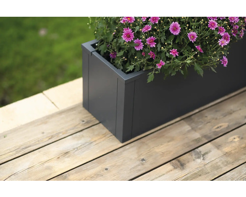 Grijze plantenbak met bloeiende bloemen op een houten terras