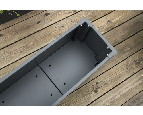 Lege, rechthoekige, grijze metalen plantenbak op houten vloer