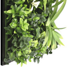 Kunstmatige plantenwand met verschillende groene bladeren en een witte bloem