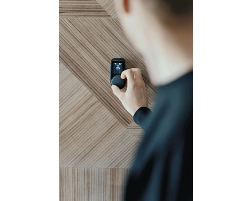 Persoon die een slimme thermostaat instelt op een houten wand