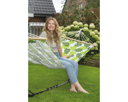 Vrouw ontspant in hangmat met bladerpatroon in de tuin