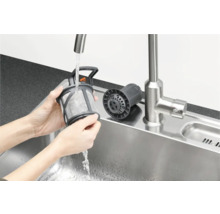 Een persoon reinigt het vaatwasmachinefilter onder stromend water in een gootsteen.