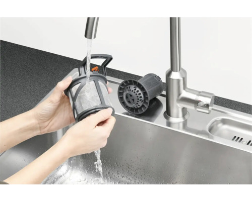 Een persoon reinigt het vaatwasmachinefilter onder stromend water in een gootsteen.
