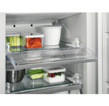 Interieur van een koelkast met transparante planken en diverse voedingsmiddelen in containers.