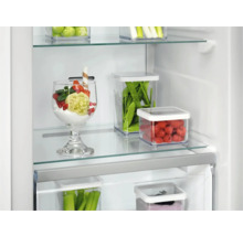 Koelkast met voedsel in transparante bakken op glazen planken