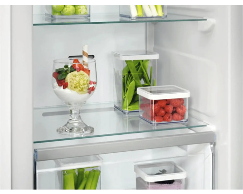 Koelkast met voedsel in transparante bakken op glazen planken