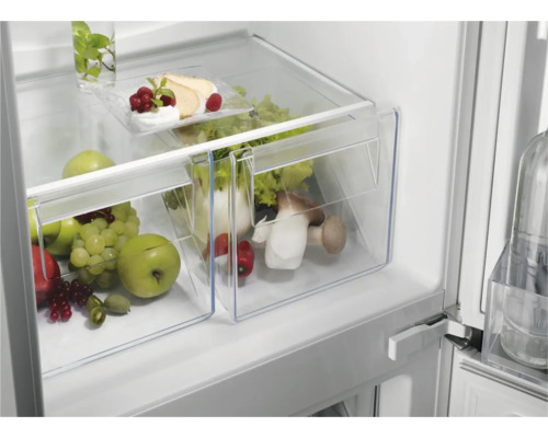 Koelkast met groentelade gevuld met fruit en groente.