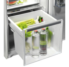 Groentelade in koelkast met sla, selderij en drinkflessen