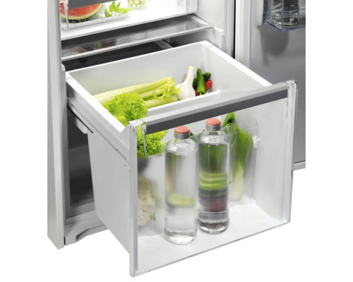 Groentelade in koelkast met sla, selderij en drinkflessen