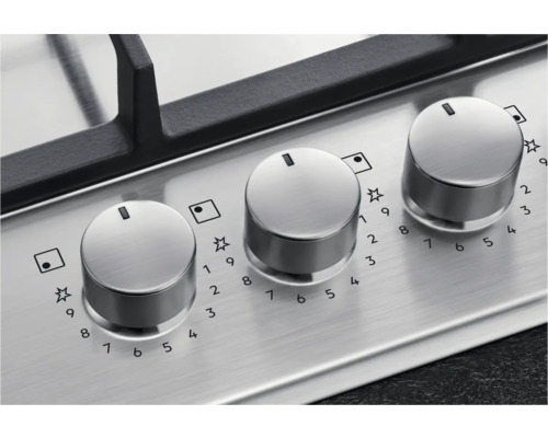 Close-up van een gaskookplaat met drie zilverkleurige bedieningsknoppen.