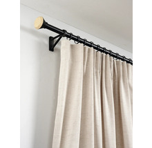 Zwarte metalen gordijnroede met eindknop in houtoptiek en beige gordijn met textuur aan ringen.