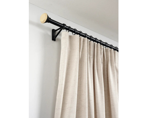 Zwarte metalen gordijnroede met eindknop in houtoptiek en beige gordijn met textuur aan ringen.