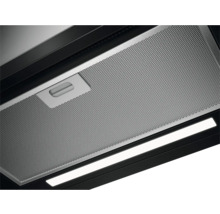 Detailopname van een metalen vetfilter met handgreep en verlichting van een afzuigkap