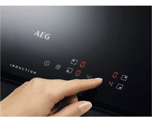 Close-up van een AEG inductiekookplaat met een hand die het vermogensniveau aanpast.